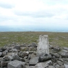 The trig point of Cross Fell with the misty haze of the Eden Valley to the west